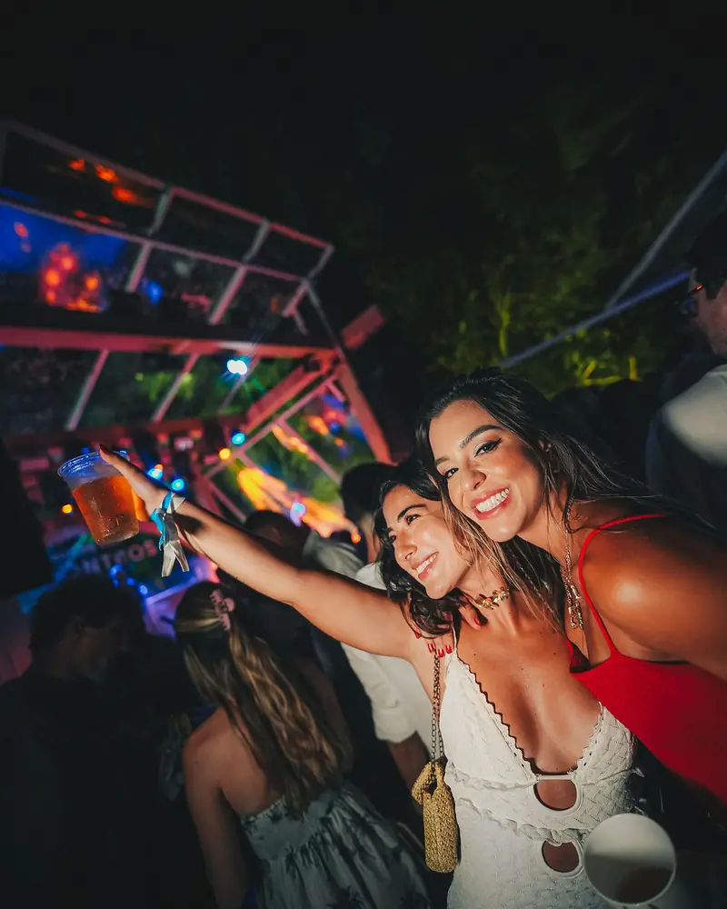Amigas sorrindo em frente à estrutura da festa