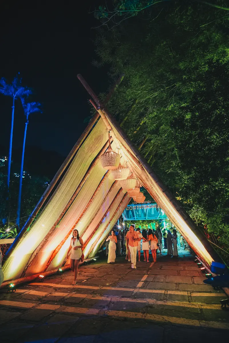 Entrada iluminada do evento com estrutura de bambu